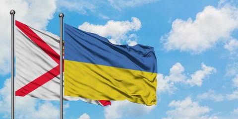 Jersey and Ukraine flag waving in the wind against white cloudy blue sky together. Diplomacy concept, international relations.