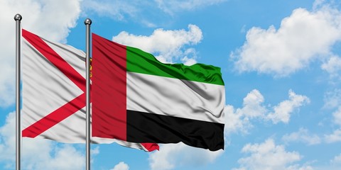 Jersey and United Arab Emirates flag waving in the wind against white cloudy blue sky together. Diplomacy concept, international relations.
