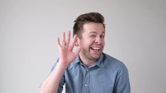 Goofy man appearing on screen and waving his hand in hello gesture.