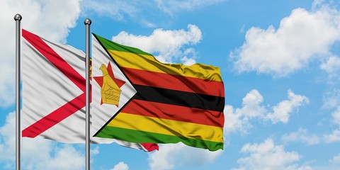 Jersey and Zimbabwe flag waving in the wind against white cloudy blue sky together. Diplomacy concept, international relations.