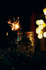  New Year, a burning sparkler in a jar with bright bokeh on a dark background