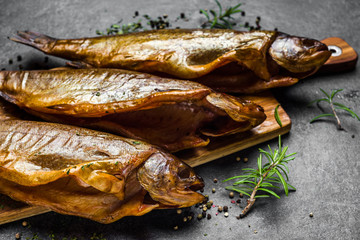 Smoked fish with spices on dark background