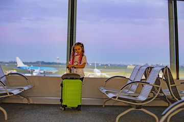 Little girl with pink hair at the airport with a suitcase