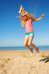 Cute girl with long hair jump high on a sand beach