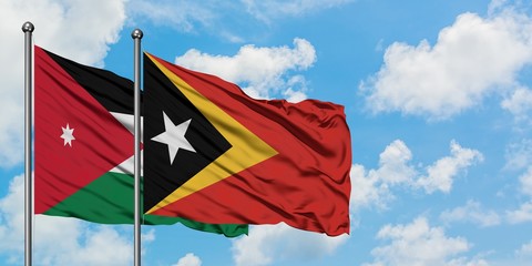 Jordan and East Timor flag waving in the wind against white cloudy blue sky together. Diplomacy concept, international relations.