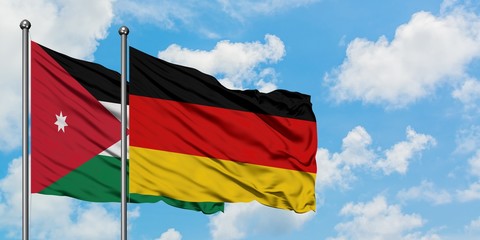 Jordan and Germany flag waving in the wind against white cloudy blue sky together. Diplomacy concept, international relations.