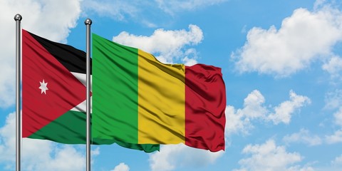 Jordan and Mali flag waving in the wind against white cloudy blue sky together. Diplomacy concept, international relations.