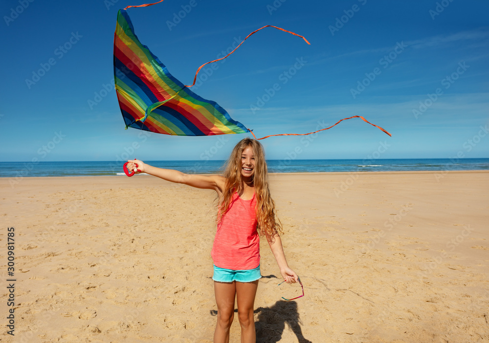 Wall mural beautiful girl stand on the beach with color kite