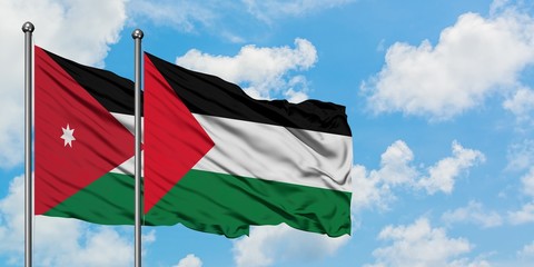 Jordan and Palestine flag waving in the wind against white cloudy blue sky together. Diplomacy concept, international relations.