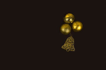 Golden New Year's toys on dark background. Christmas balls and bell. Merry Christmas and Happy New Year decoration concept