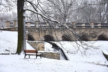Bench and bridge in snowy park - Winter in Prague