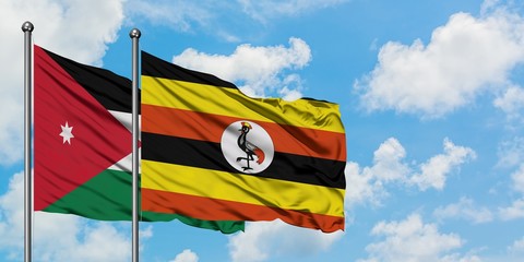 Jordan and Uganda flag waving in the wind against white cloudy blue sky together. Diplomacy concept, international relations.