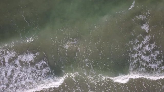 A flying camera captures a sea wave on a sandy beach in Vietnam.
