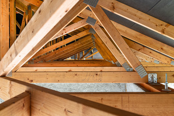 Roof trusses covered with a membrane on a detached house under construction, view from the inside, visible roof elements and truss plates. - obrazy, fototapety, plakaty