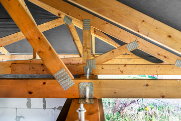 Roof trusses covered with a membrane on a detached house under construction, view from the inside, visible roof elements and truss plates.