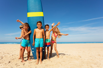 Boy with friends stand by surfboard on the beach