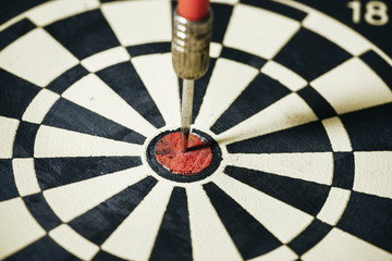 Dart arrow hitting in the target center of dartboard