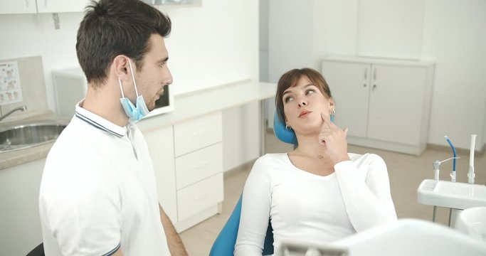Dentist and lady patient talking in stomatology clinic, woman telling about problems, oral cavity checkup