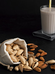 Almond milk with almonds on a black background. Close-up. Healthy eating concept. Copy space Natural light.