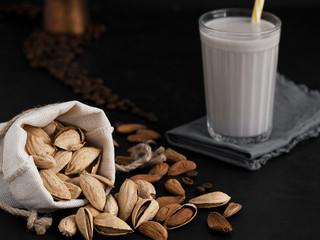 Almond milk with almonds on a black background. Coffee beans and espresso cezve. Close-up. Healthy eating concept. Copy space Natural light.