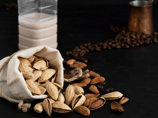 Almond milk with almonds on a black background. Coffee beans and espresso cezve. Close-up. Healthy eating concept. Copy space Natural light.