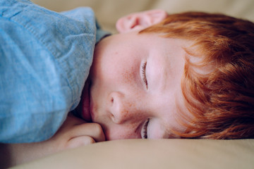 Obraz na płótnie Canvas Child dreaming. Family care and childcare concept. Lovely red haired son taking a nap at his bedroom. Little kid sleeping in bed at Christmas eve dreaming about Santa Claus. Family care concept.