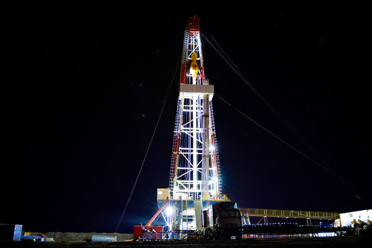 Oil And Gas Drilling Rig. Oil Drilling Rig Operation On The Oil Platform In Oil And Gas Industry. Beautiful Night View Of Derrick Drilling Rig In Offshore Gas Field.