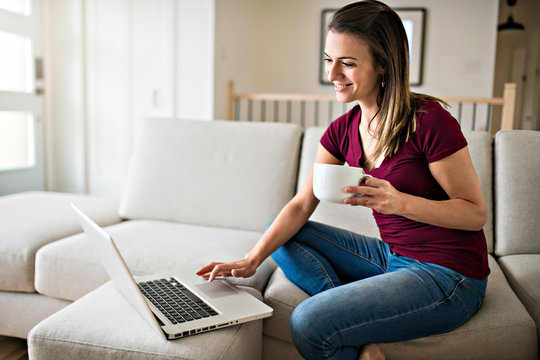 Brunette having good time on the living room with coffee and laptop