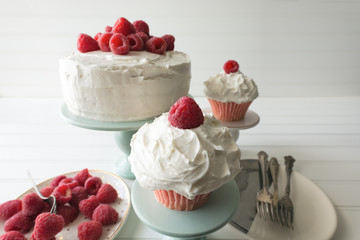 Raspberry cupcakes and whole cake decorated with fresh raspberries and vanilla frosting. 