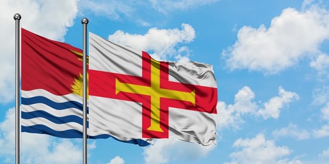 Kiribati and Guernsey flag waving in the wind against white cloudy blue sky together. Diplomacy concept, international relations.
