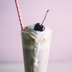 Close up of a cherry on a root beer float with pink paper straw with heart pattern. 