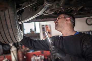 Obraz na płótnie Canvas Auto master mechanic checks condition of the brakes and wheels