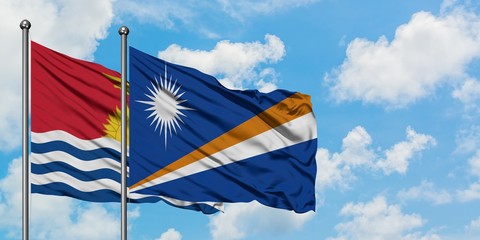 Kiribati and Marshall Islands flag waving in the wind against white cloudy blue sky together....