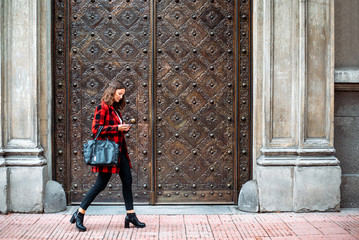 pretty young woman walking on the street using smartphone