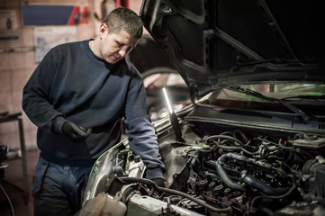Obraz na płótnie Canvas Car mechanic repairer service technician checks and repairs auto engine