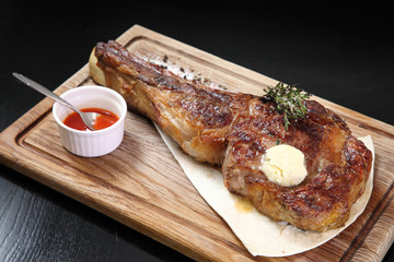Medium-roasted steak cut into pieces on a wooden board with sauce and seasonings. Delicious steak. Beef steak medium rare on vegetable cushion. Beef steak on wooden plate. 