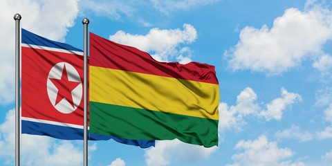 North Korea and Bolivia flag waving in the wind against white cloudy blue sky together. Diplomacy concept, international relations.