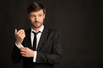 Handsome Businessman In Suit Buttoning Shirt Sleeve Standing In Studio