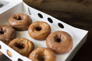 Half a dozen glazed cake donuts in a white bakery box. 
