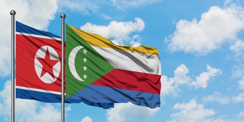 North Korea and Comoros flag waving in the wind against white cloudy blue sky together. Diplomacy concept, international relations.