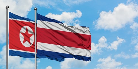 North Korea and Costa Rica flag waving in the wind against white cloudy blue sky together. Diplomacy concept, international relations.
