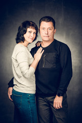 Playful mature married couple photographed in the studio. Handsome man in jeans and smiling woman in shirt playing