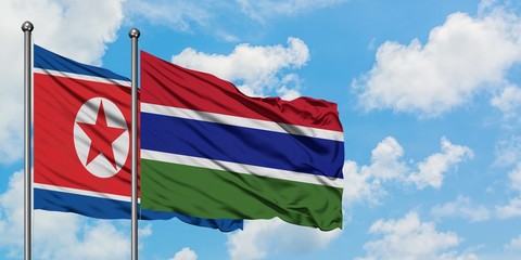 North Korea and Gambia flag waving in the wind against white cloudy blue sky together. Diplomacy concept, international relations.