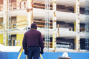 Surveyor engineer uses a total station at a construction site. Geodetic works. Building construction