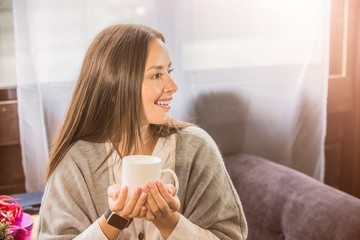 a girl in a cafe holding a mug of coffee