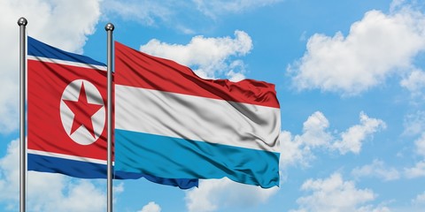 North Korea and Luxembourg flag waving in the wind against white cloudy blue sky together. Diplomacy concept, international relations.