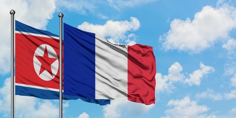 North Korea and Reunion flag waving in the wind against white cloudy blue sky together. Diplomacy concept, international relations.