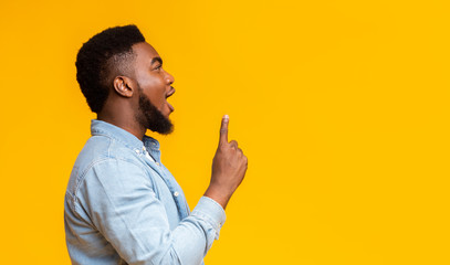 African guy looking and pointing upwards at copy space