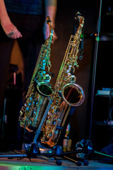 Zwei Saxofone auf einem Ständer auf der Bühne während eines Konzerts, dämmrig beleuchtet.