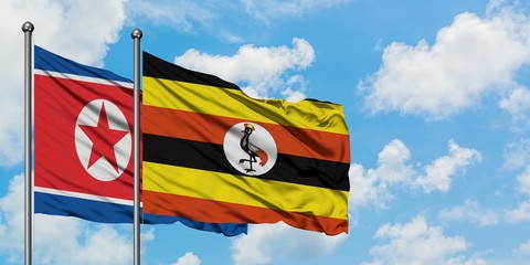 North Korea and Uganda flag waving in the wind against white cloudy blue sky together. Diplomacy concept, international relations.